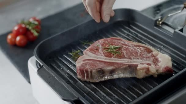 Chef przyprawiając smażenia mięsa na Griddle. Zbliżenie mężczyzna ręce gotowanie stek. — Wideo stockowe