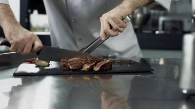 Erkek şef mutfak restoranında biftek kesiyor. Closeup şef eller et kesme
