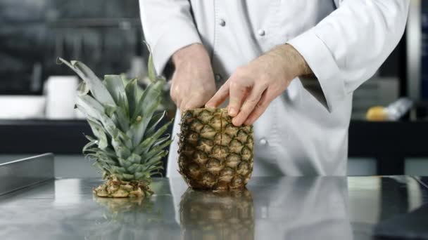 Koch schneidet Ananas in Zeitlupe. Großaufnahme Koch Hände schneiden frisches Obst. — Stockvideo