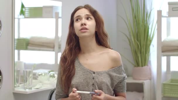Niespokojna młoda kobieta wygląda na wynik testu ciążowego w łazience. Nieplanowana ciąża — Wideo stockowe