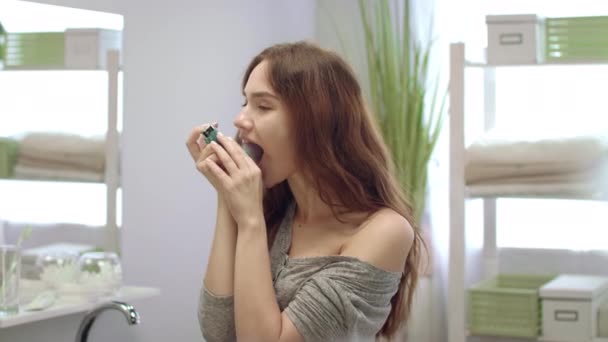 Mujer alegre rociando aerosol oral para el aliento fresco en la boca en el cuarto de baño — Vídeos de Stock