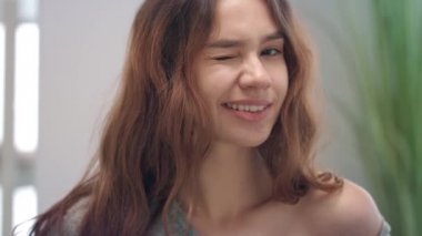 Göz kırpan ve kameraya gülümseyen çekici bir kadın portresi.