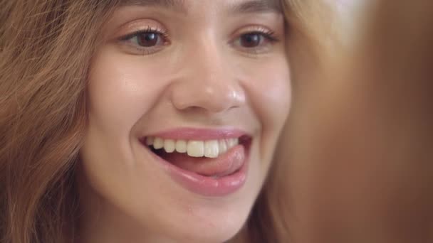 Счастливая женщина облизывает белые зубы с языком перед ванной зеркало в доме — стоковое видео
