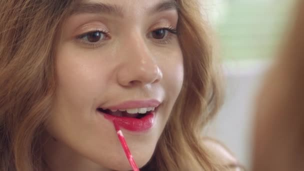 Młoda kobieta za pomocą płynnej szminki do makijażu usta przednie lustro łazienka — Wideo stockowe