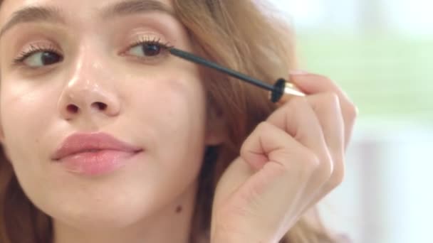 Femme heureuse utilisant une brosse à mascara pour les cils miroir de salle de bain avant dans la maison — Video