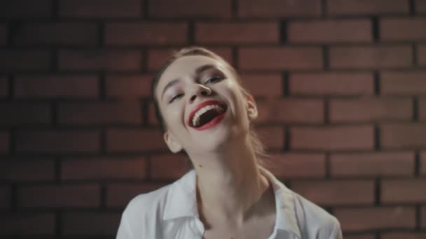 Χαρούμενη γυναίκα που γελάει και ποζάρει στην κάμερα στο στούντιο με τούβλο στον τοίχο — Αρχείο Βίντεο