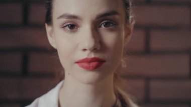 Şaşırmış kadın, tuğla duvar arka planında şaşkınlıktan ağzını açtı.