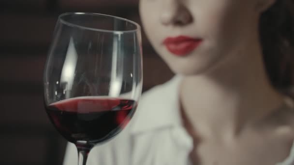 Mujer atractiva sosteniendo en copa de vino de la mano. Chica bonita bebiendo vino tinto — Vídeos de Stock