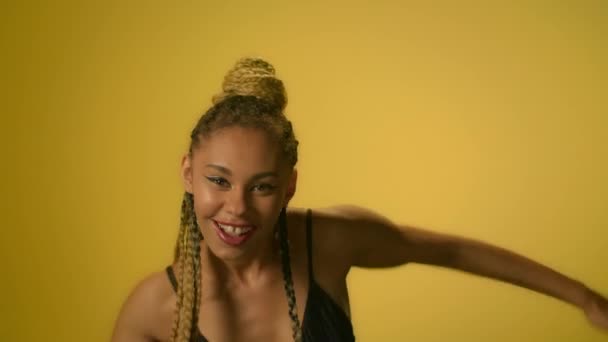 Африканская женщина с африканской прической танцует хип-хоп танец на желтой стене — стоковое видео
