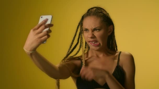 Afro amerikansk kvinna poserar för mobila Selfie ingen smartphone på gul bakgrund — Stockvideo