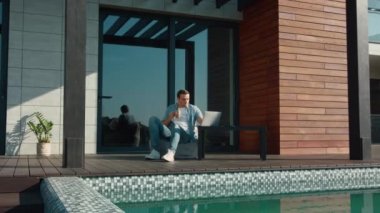 Lüks evde dizüstü bilgisayar kullanan mutlu adam. Evde teknolojiyi kullanan iş adamı