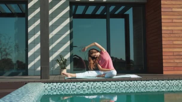 Mujer joven haciendo ejercicio de yoga cerca de la piscina. Mujer de negocios hacer yoga después del trabajo — Vídeos de Stock