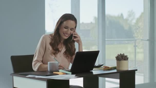 Mulher de negócios a trabalhar no computador portátil. Concentrado senhora falando telefone . — Vídeo de Stock
