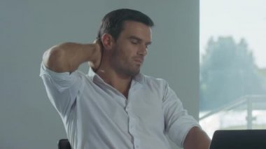 İş adamı uzak bir işyerinde dinlenmeye çalışıyor. Dizüstü bilgisayarda çalışan yorgun adam.