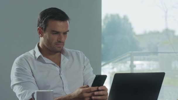 Hombre de negocios buscando teléfono móvil en el lugar de trabajo. Hombre concentrado teniendo descanso . — Vídeos de Stock