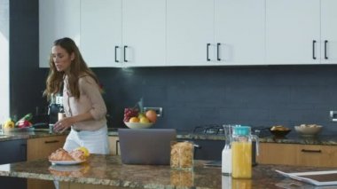 İş kadını aceleyle kahvaltı hazırlıyor. Meşgul kişi cep telefonu kontrol