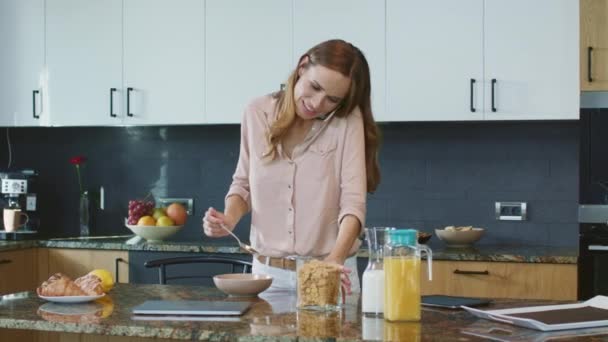 Lycklig kvinna förbereder hälsosam frukost. Avslappnad person talar på mobiltelefon — Stockvideo