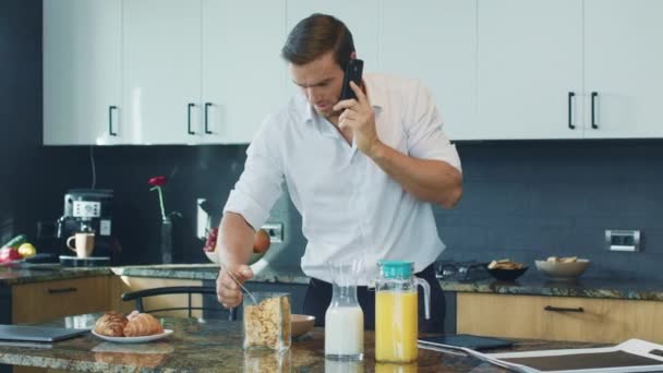 Homme heureux préparant le petit déjeuner dans la cuisine. Personne détendue parlant au téléphone . — Video