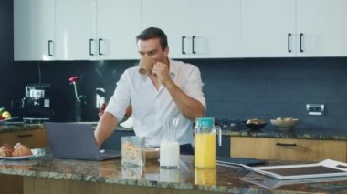 İş adamı büyük mutfakta video izliyor. Dizüstü bilgisayara bakan sürpriz kişi.