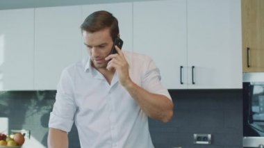 Lüks mutfakta konuşan gülümseyen adam. Konsantre adam öğle yemeği hazırlanıyor.
