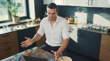 Mutfakta bilgisayar başında konuşan iş adamı. Çevrimiçi sohbet edemeye niçin gülümseyen kişi