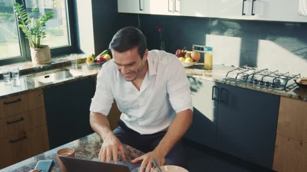 Hombre alegre hablando en el portátil en la cocina. Sonriente persona tener chat en línea . — Vídeos de Stock