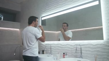Mutlu adam banyoda diş fırçalıyor. Diş taşıyan konsantre erkek kişi.