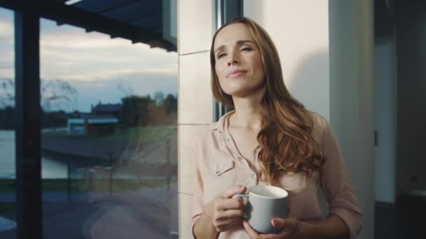 Lycklig kvinna vistas nära fönster efter arbetsdag. Avslappnad kvinna med vila — Stockvideo