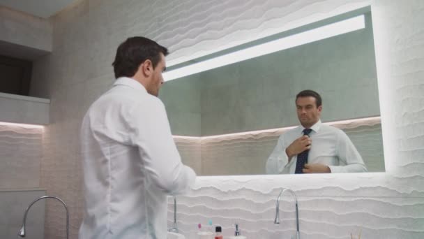 Ένας επιχειρηματικός άντρας φορώντας γραβάτα στο πολυτελές μπάνιο. Ευτυχισμένος άνθρωπος ντύνει τον εαυτό του στο σπίτι — Αρχείο Βίντεο