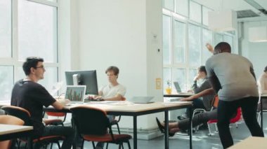 Mutlu arkadaşlar birlikte çalışma etrafında sandalyede hareket. Ofisten kaçan siyah adam.