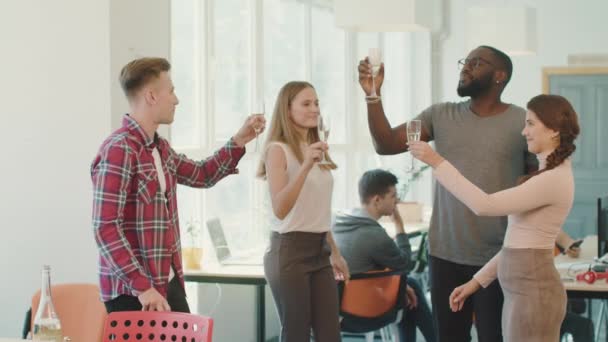 Gente feliz dando brindis en el espacio de coworking. Sonriendo amigos bebiendo juntos — Vídeo de stock