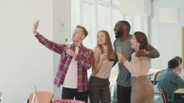 Birlikte çalışma alanında selfie çeken gülümseyen insanlar. Neşeli takım kamerada poz.