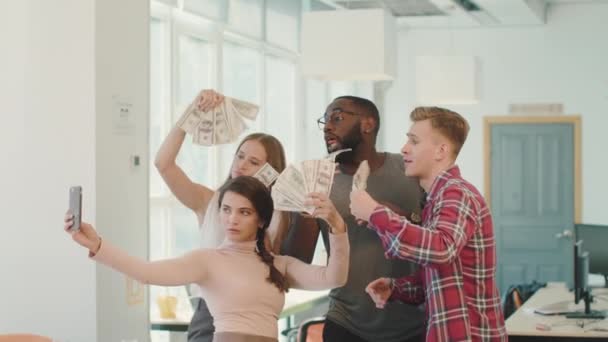 Os jovens gozam com o dinheiro no coworking. Pessoas felizes tirando selfie . — Vídeo de Stock