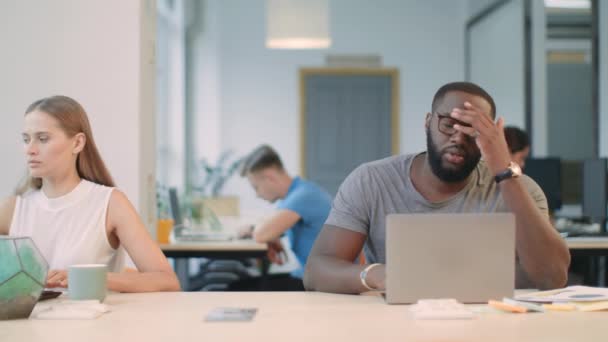 オフィスのラップトップコンピュータで悪いニュースを読んでいる若者。ショックを受けたアフリカ人 — ストック動画