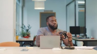 Kamerayı dizüstü bilgisayara bağlayan Afrikalı adam. Bilgisayara fotoğraf kaydeden adam