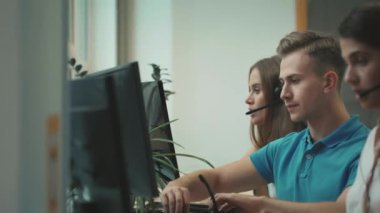 Çağrı merkezine kulaklık yerleştiren genç operatör. Müşteri ile konuşan gülümseyen adam