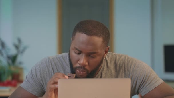 African man eating chocolate cookie at workplace. Portrait of guy eating cookie — Stock Video