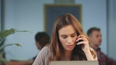 Mutsuz iş kadını ortak çalışma alanında cep telefonu konuşuyor. Kızgın kadın