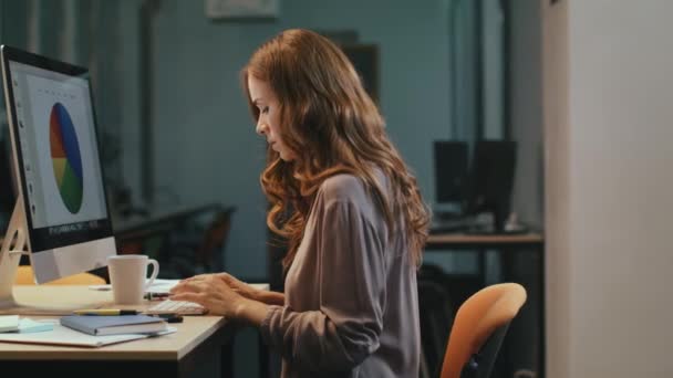 Удивлённая деловая женщина смотрит на финансовый отчет на экране компьютера ночью — стоковое видео