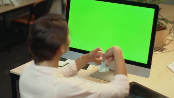 若い女性は、オフィスで緑色の画面を持つコンピュータ上でビデオをオンライン呼び出します — ストック動画
