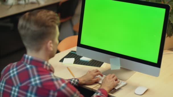 Geschäftsmann tippt auf Computer mit grünem Bildschirm. Junger Mann arbeitet am Computer — Stockvideo