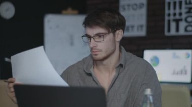 Karanlık ofiste bilgisayarın yanında çalışan düşünceli bir iş adamı.