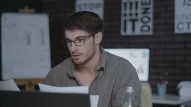 Mutlu iş adamı karanlık ofiste dizüstü bilgisayarın önünde rapor kontrol ediyor..