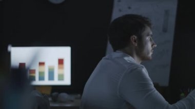 Finansal grafiği gece ofisinde izleyen odaklanmış iş analisti