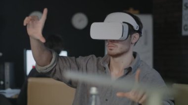 VR gözlük kullanan genç bir programcı. Tasarımcı gece ofisinde 3B oyunu test ediyor