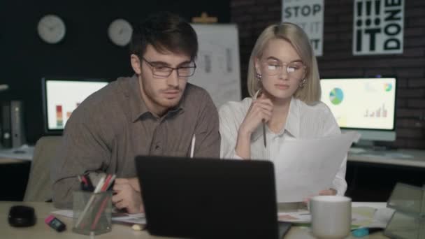 Casal de negócios assistindo juntos relatório financeiro computador frontal no escritório escuro — Vídeo de Stock