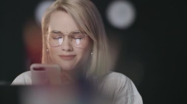 Gülümseyen iş kadını gece ofisinde akıllı telefondan mesaj yazıyor..