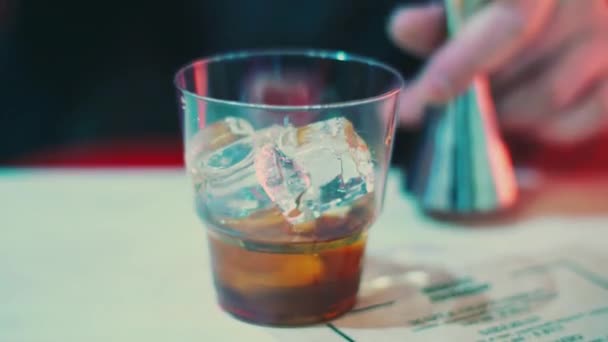 Barman pouring alcoholic drink into glass with ice cubes. Barman making whiskey — Stock Video