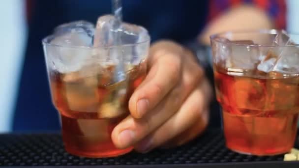 Barman připravuje koktejl v baru. Barmana míchání alkoholických nápojů s ledem — Stock video