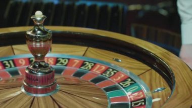 Rulet tekerleği ve casino beyaz topu ile krupiye el. İnsanlar kumar oynuyor.